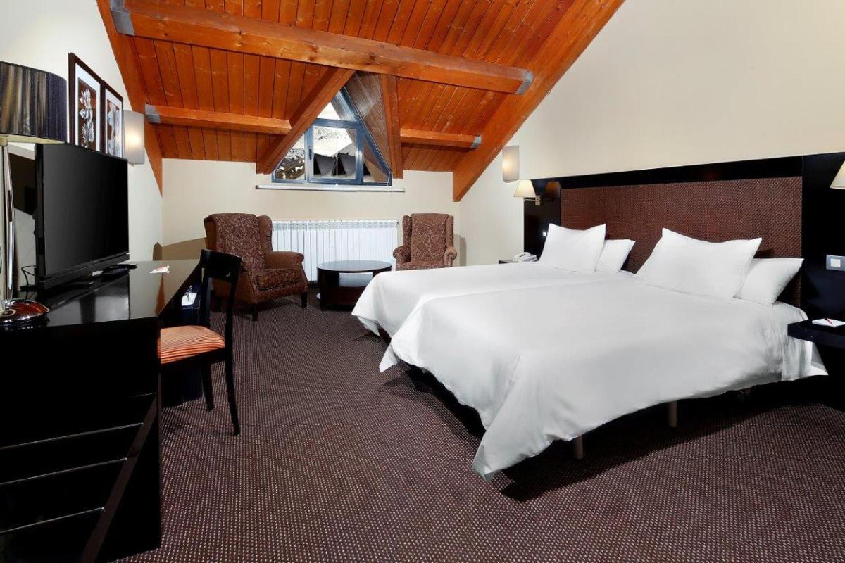 Una habitación de hotel con una cama grande y un televisor. en HG Alto Aragón, en Formigal 42 fotos más