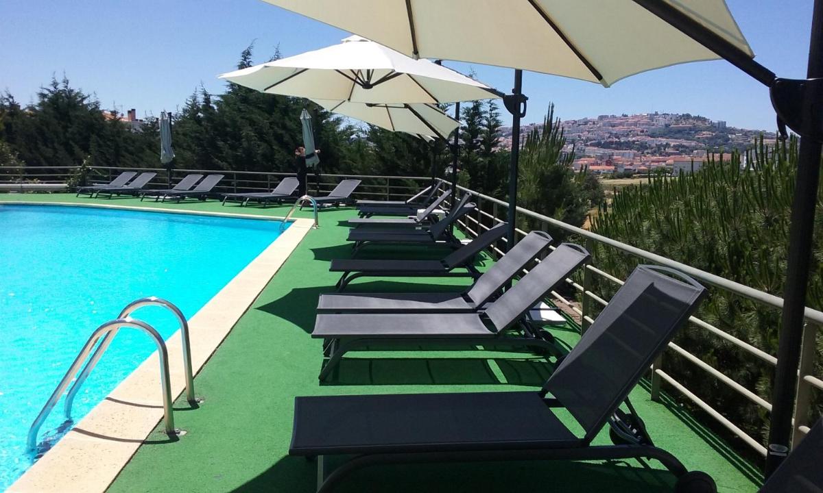 uma fileira de espreguiçadeiras ao lado de uma piscina em Hotel Lusitania Congress & Spa na Guarda