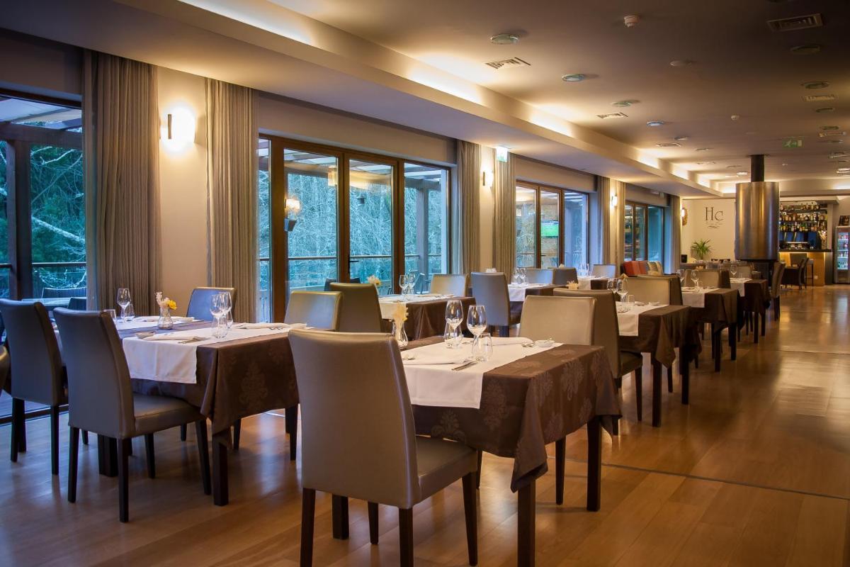 uma sala de jantar com mesas, cadeiras e janelas em Hotel Rural Vale Do Rio em Oliveira de Azemeis