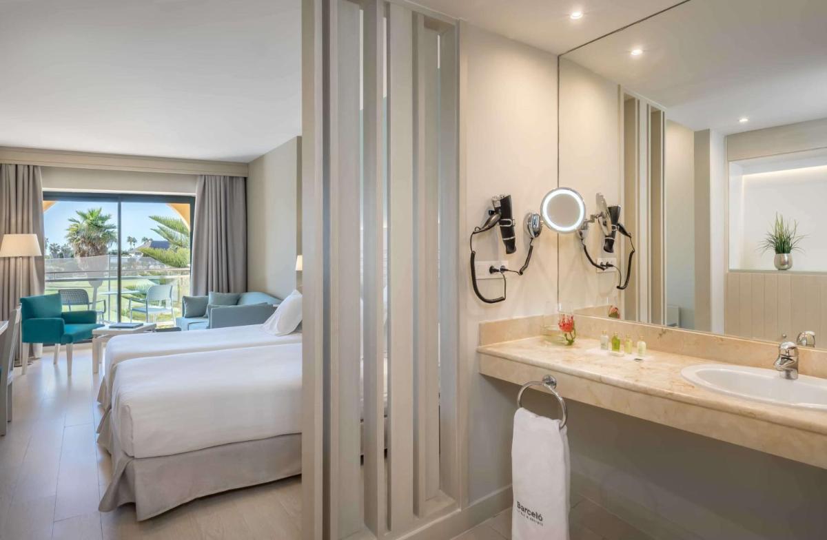 Habitación de hotel con cama, lavabo y espejo en Barceló Costa Ballena Golf & Spa, en Costa Ballena