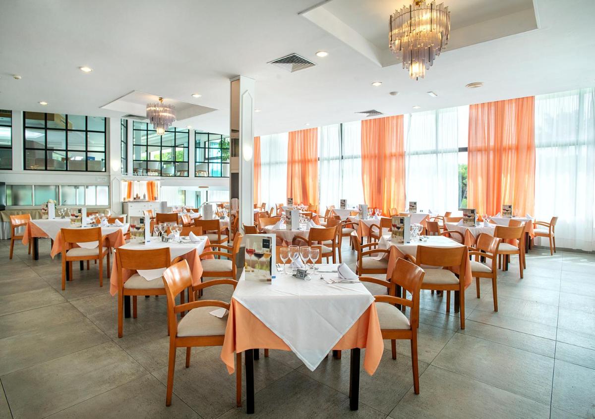 Un comedor con mesas y sillas y ventanas. en Exagon Park, en Can Picafort