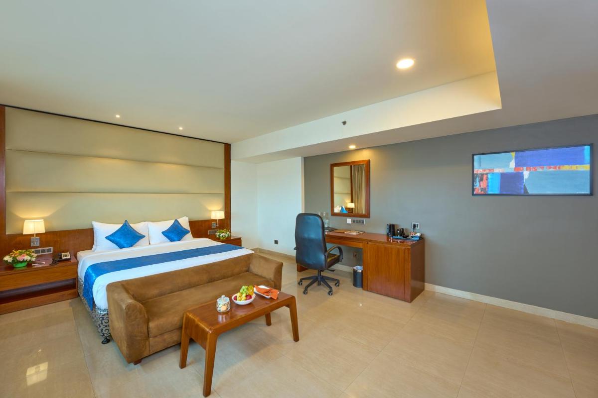 a hotel room with a bed and a desk at The Raviz Calicut in Kozhikode