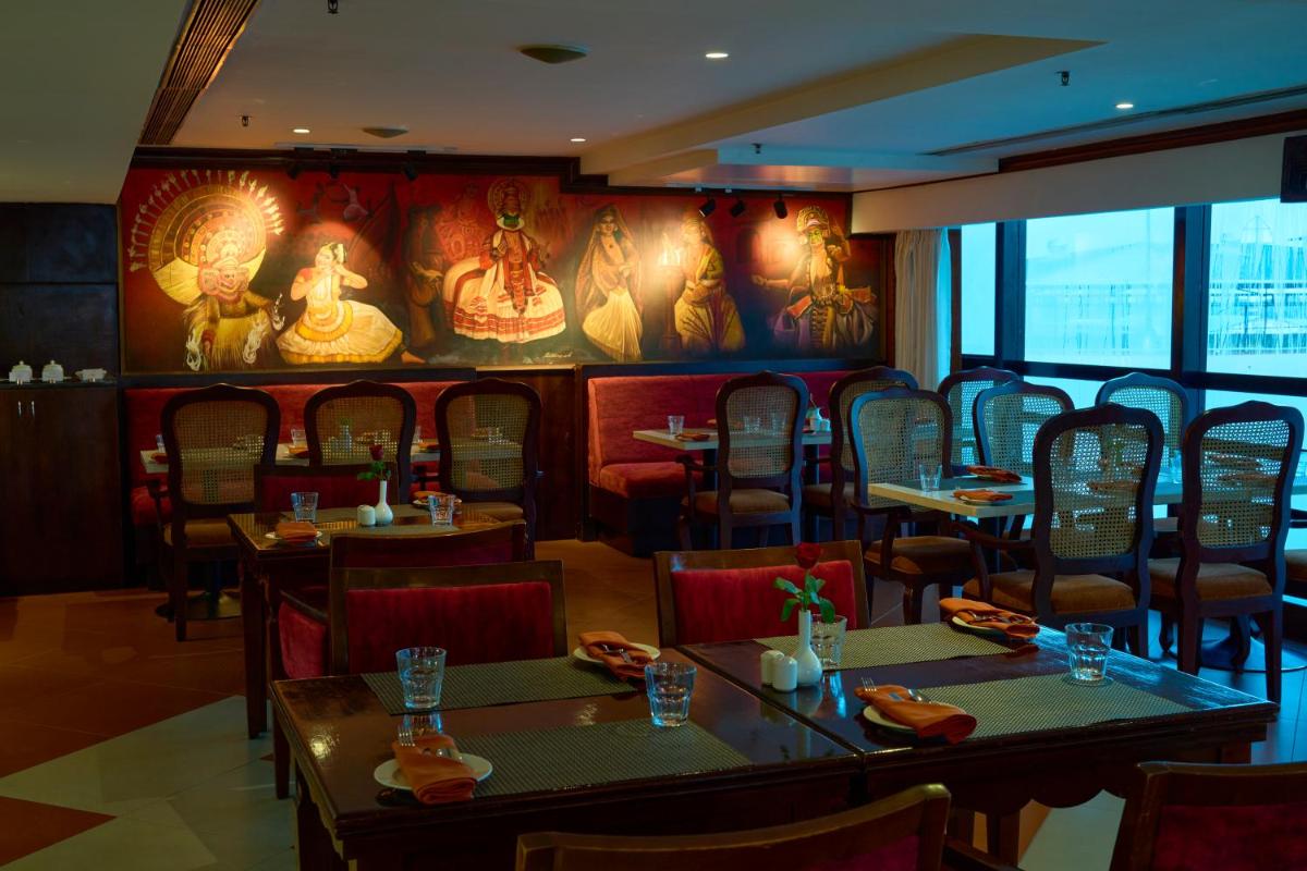 a restaurant with tables and chairs and a wall with paintings at The Raviz Calicut in Kozhikode