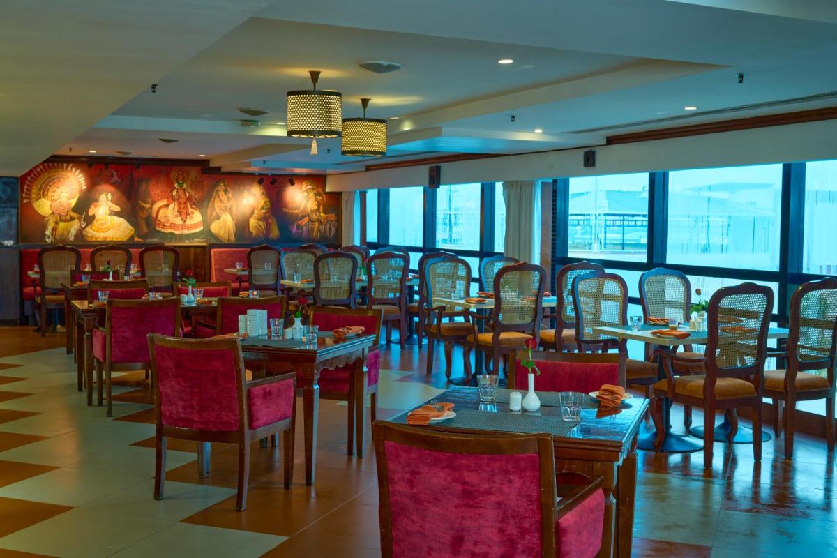 a dining room with tables and chairs and windows at The Raviz Calicut in Kozhikode