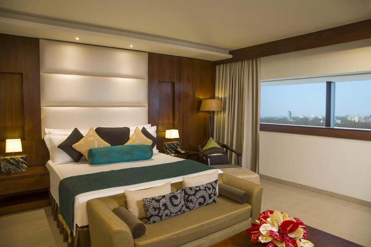 a bedroom with a bed and a couch and a window at The Raviz Calicut in Kozhikode