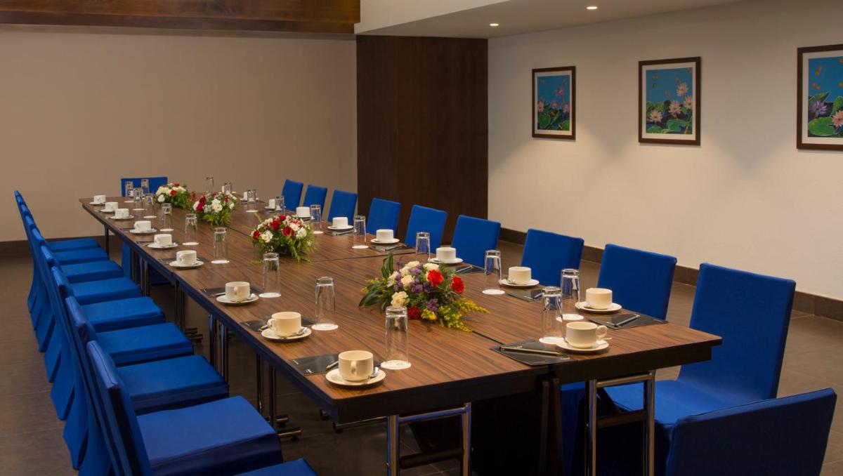 a long table in a room with blue chairs at The Raviz Calicut in Kozhikode