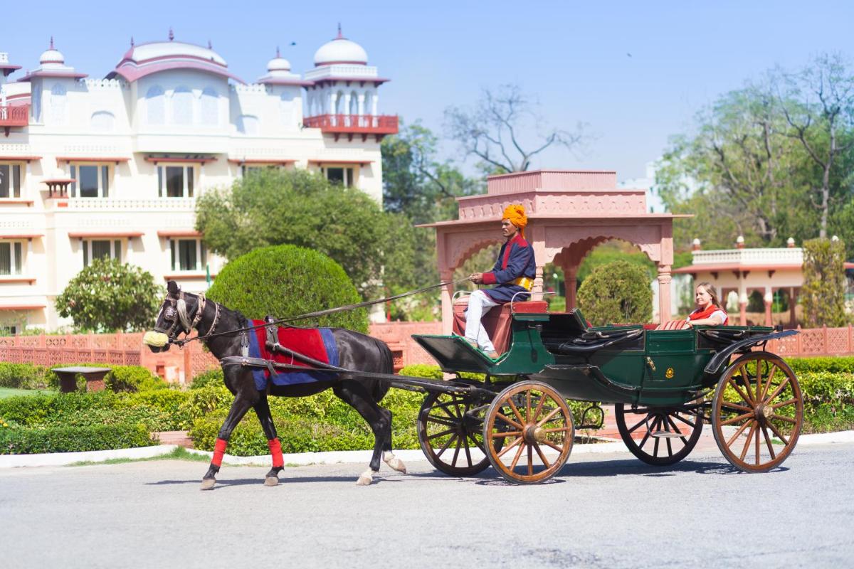 a man riding a horse drawn carriage down a street at Jai Mahal Palace in Jaipur
