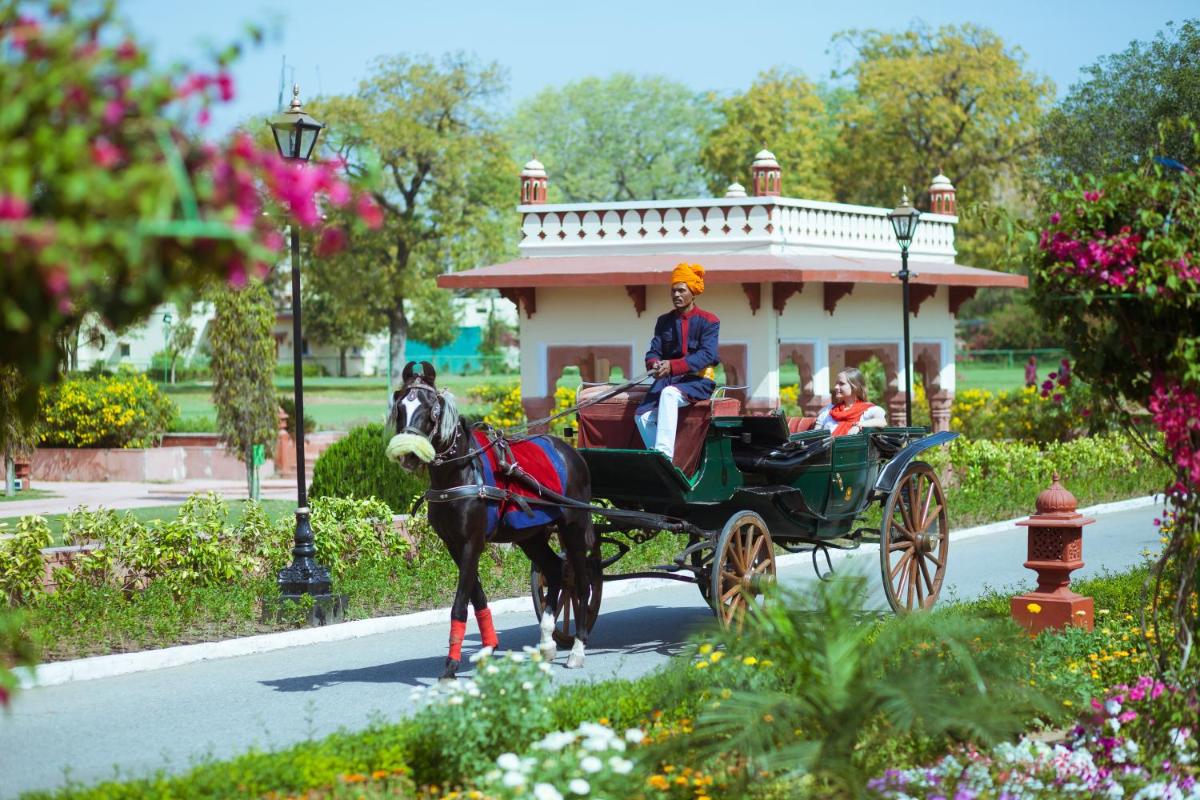 a woman riding a horse drawn carriage down a street at Jai Mahal Palace in Jaipur