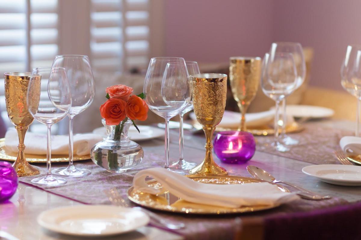 a table with wine glasses and plates and flowers at Jai Mahal Palace in Jaipur