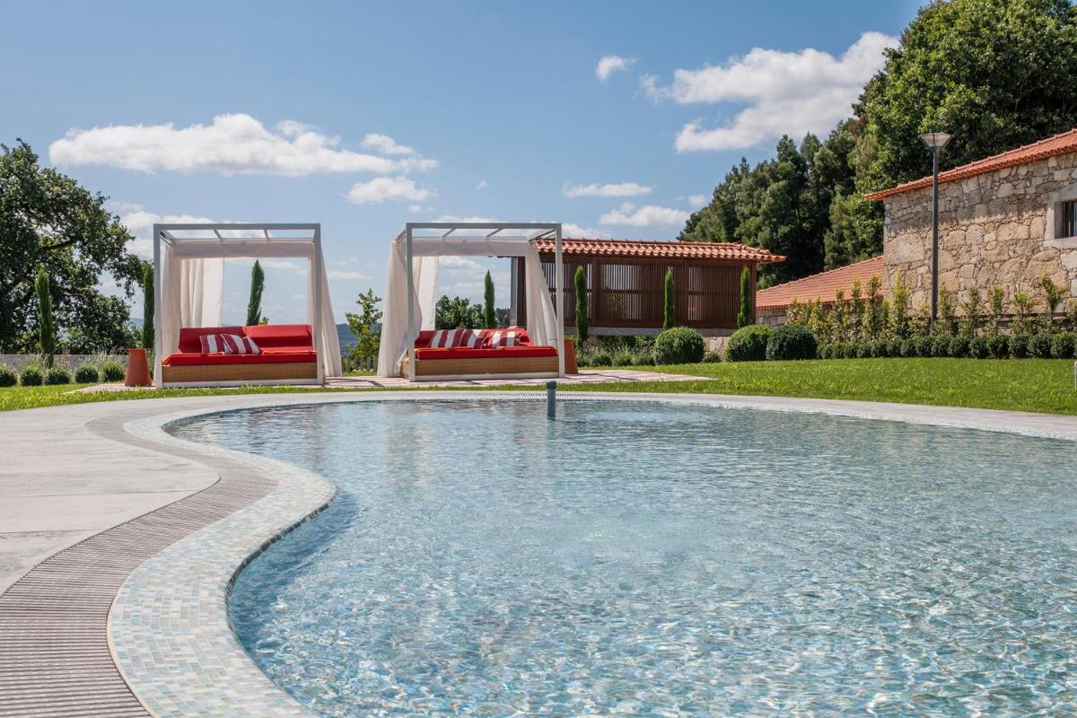 uma piscina com duas cadeiras vermelhas em um quintal em Solar de Vila Meã em Barcelos