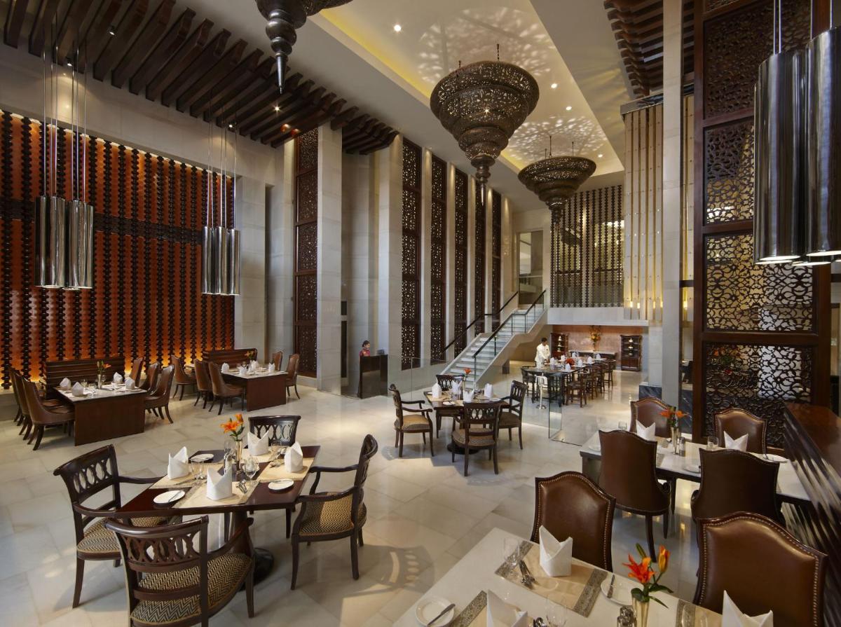 a restaurant with tables and chairs and a staircase at ITC Mughal, A Luxury Collection Resort & Spa, Agra in Agra