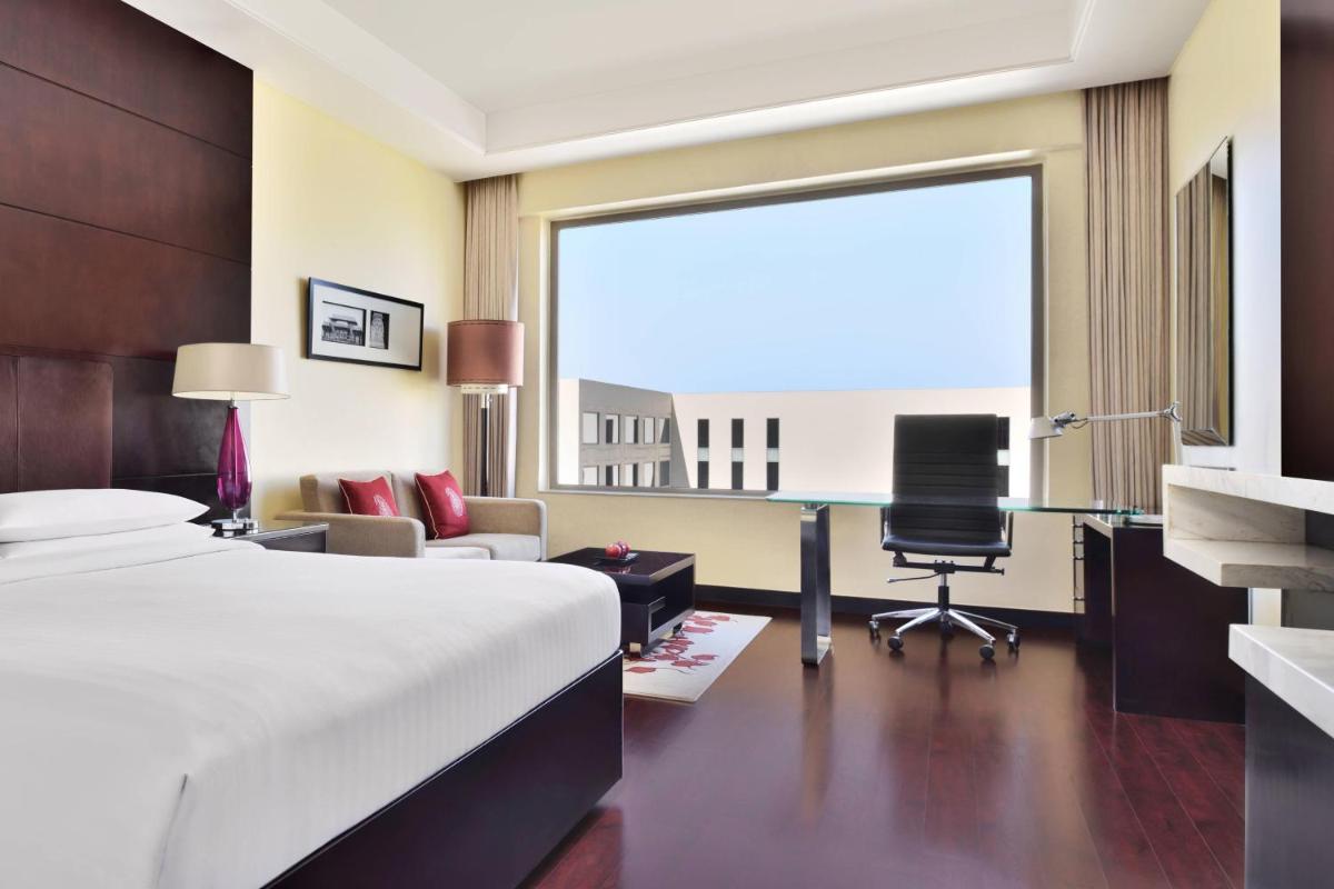 a bedroom with a bed and a desk and a chair at Jaipur Marriott Hotel in Jaipur a bedroom with a bed and a desk and a chair at Jaipur Marriott Hotel in Jaipur