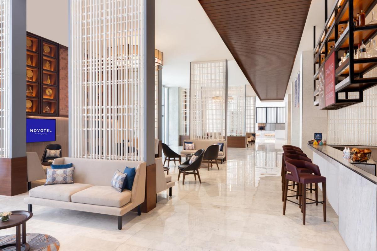 a lobby with chairs and tables in a building at Novotel Jaipur Convention Centre in Jaipur