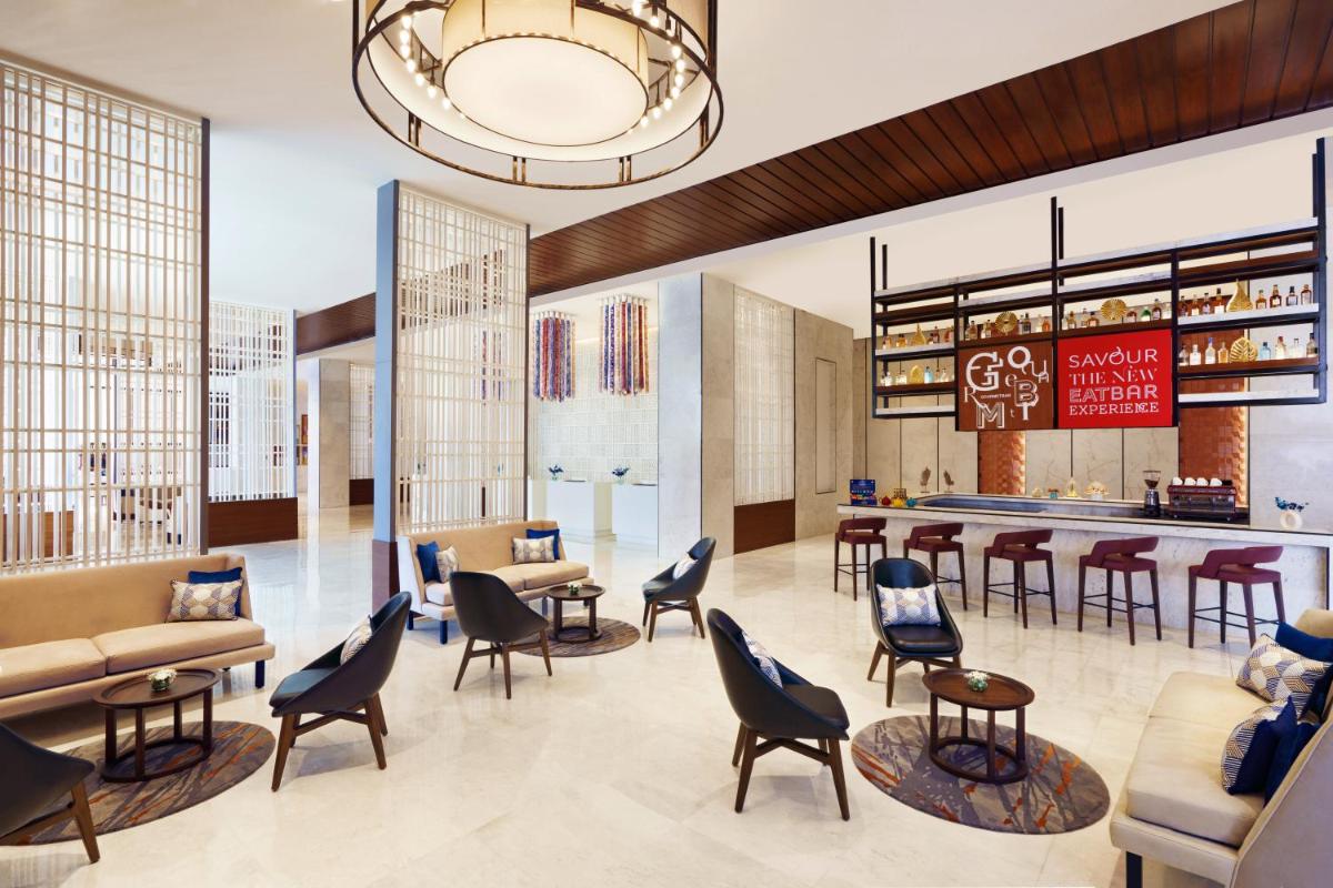 a lobby with chairs and tables and a bar at Novotel Jaipur Convention Centre in Jaipur