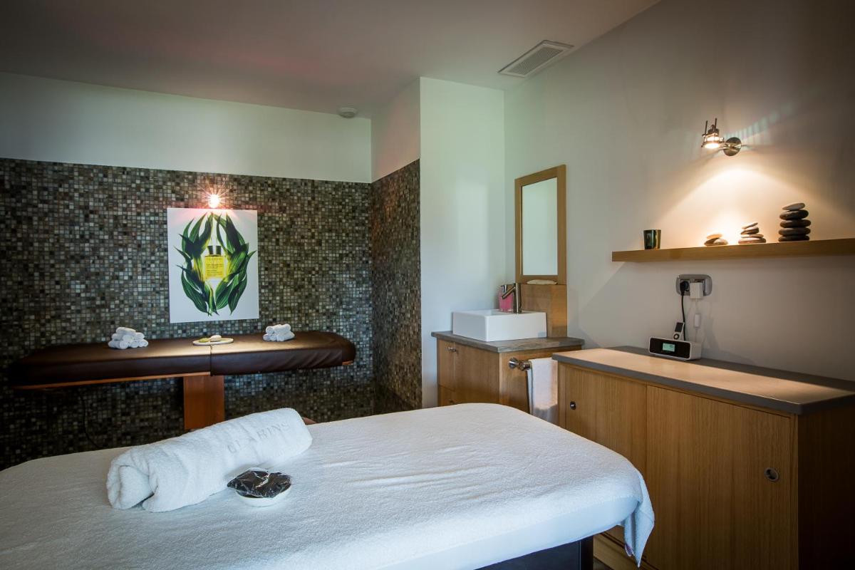 Cette chambre comprend un lit, un lavabo et un miroir. dans l'établissement Le Clos Saint-Martin Hôtel & Spa, à Saint-Martin-de-Ré