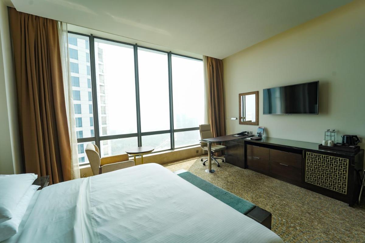 a hotel room with a bed and a desk with a television at The Westin Kolkata Rajarhat in Kolkata a hotel room with a bed and a desk with a television at The Westin Kolkata Rajarhat in Kolkata