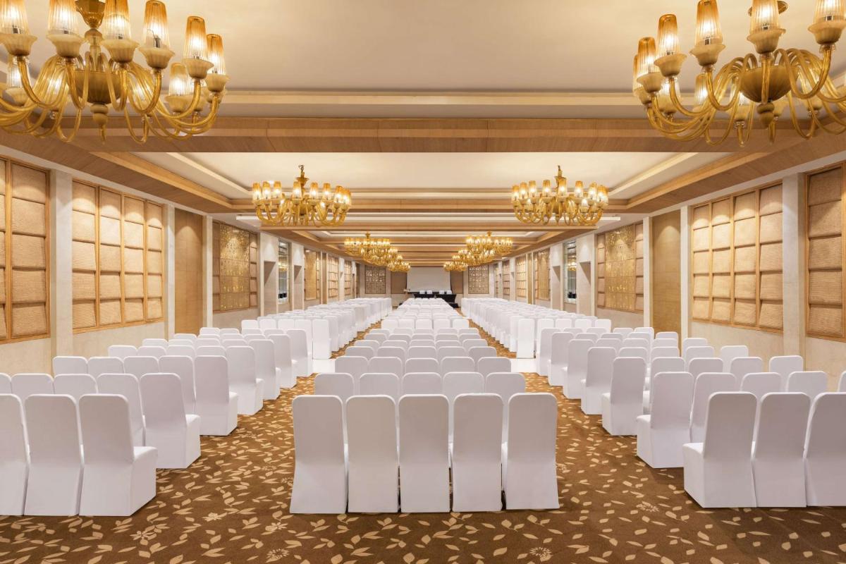 a banquet hall with white chairs and chandeliers at Radisson Blu Hotel New Delhi Dwarka in New Delhi a banquet hall with white chairs and chandeliers at Radisson Blu Hotel New Delhi Dwarka in New Delhi