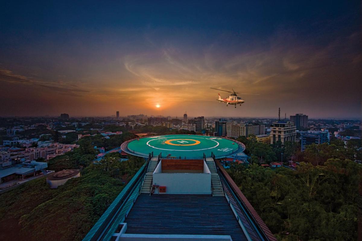 a helicopter flying over a building with a sunset at ITC Gardenia, a Luxury Collection Hotel, Bengaluru in Bengaluru a helicopter flying over a building with a sunset at ITC Gardenia, a Luxury Collection Hotel, Bengaluru in Bengaluru