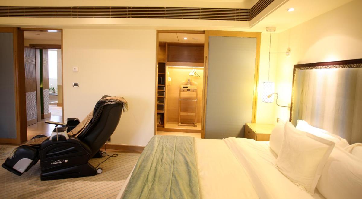 a hotel room with a bed and a chair at ITC Gardenia, a Luxury Collection Hotel, Bengaluru in Bengaluru a hotel room with a bed and a chair at ITC Gardenia, a Luxury Collection Hotel, Bengaluru in Bengaluru