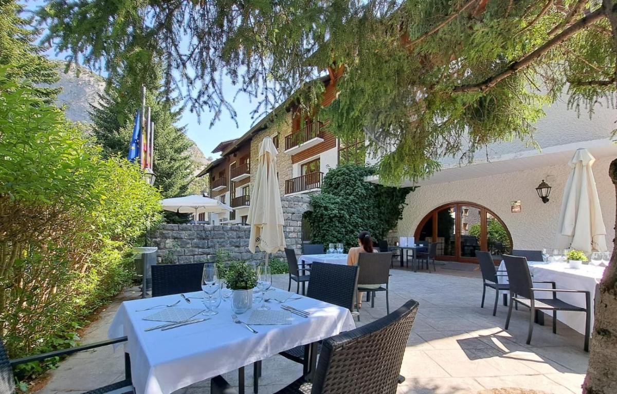 una mesa con mesas y sillas blancas frente a un edificio en Hotel & Spa Real Villa Anayet, en Canfranc-Estación