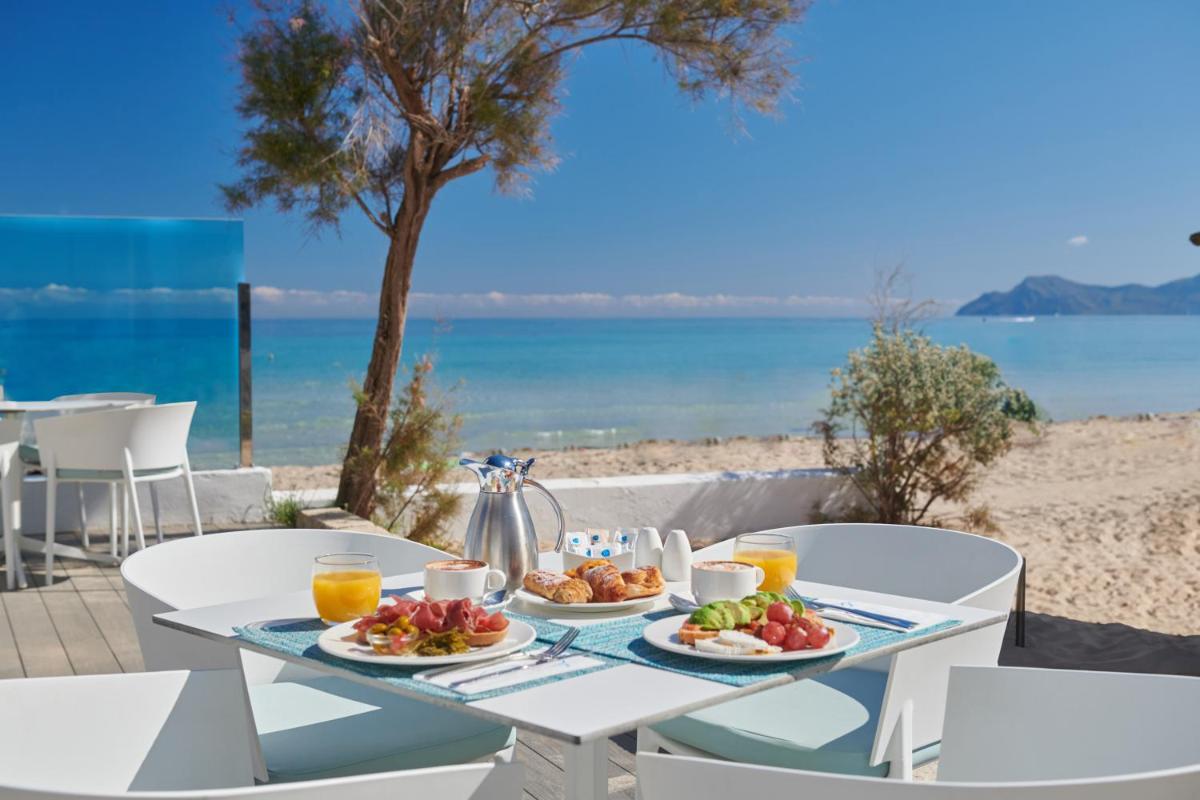 Una mesa con dos platos de comida en la playa. en The Sea Hotel by Grupotel - Adults Only, en Can Picafort