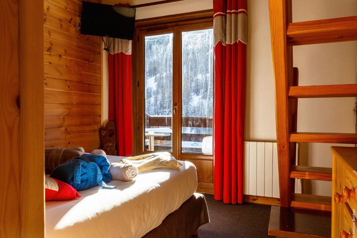 une chambre avec un lit avec des rideaux rouges et une fenêtre dans l'établissement Hotel Spa L'Equipe, à Molines-en-Queyras
