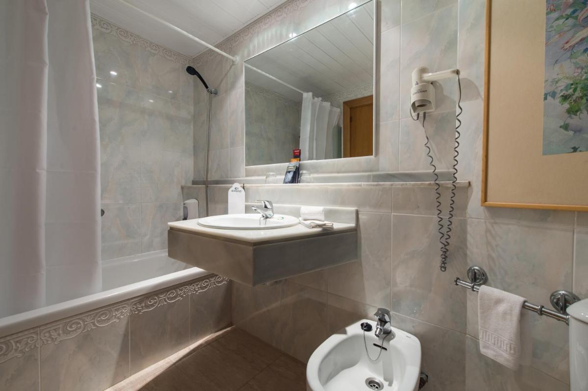 Un baño con lavabo, inodoro y espejo. en Exagon Park, en Can Picafort