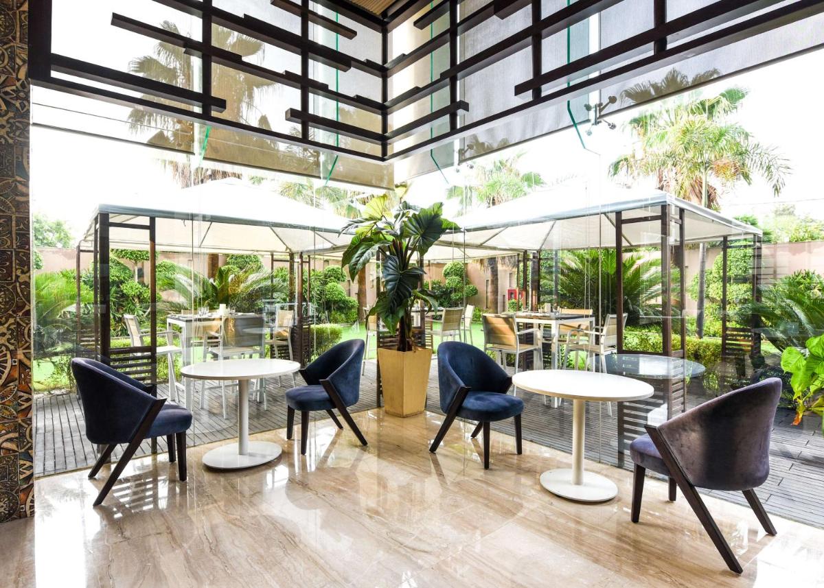 a restaurant with tables and chairs and a large window at DoubleTree by Hilton Gurugram Baani Square in Gurgaon