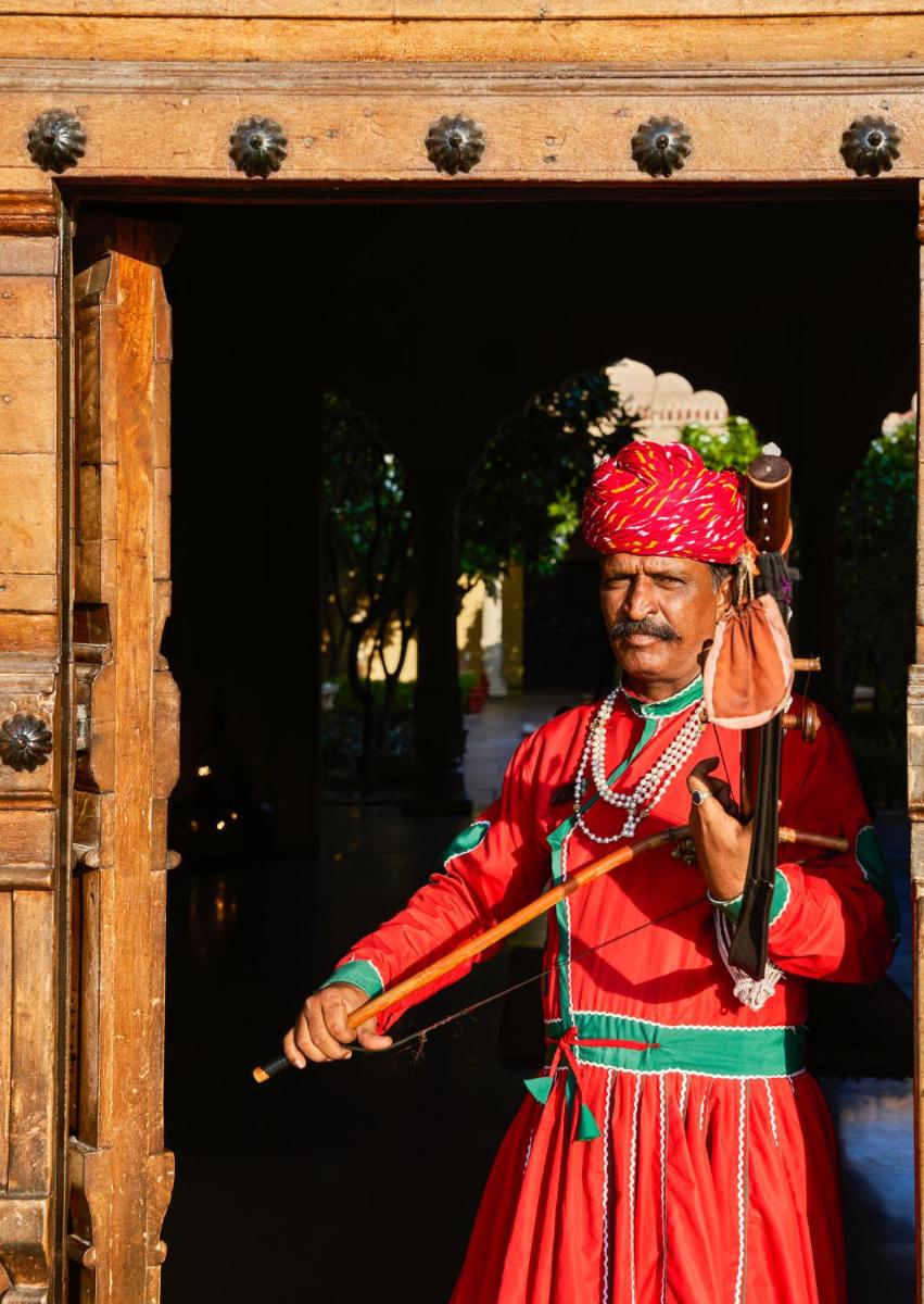 a man in a red dress holding a stick at Fairmont Jaipur in Jaipur