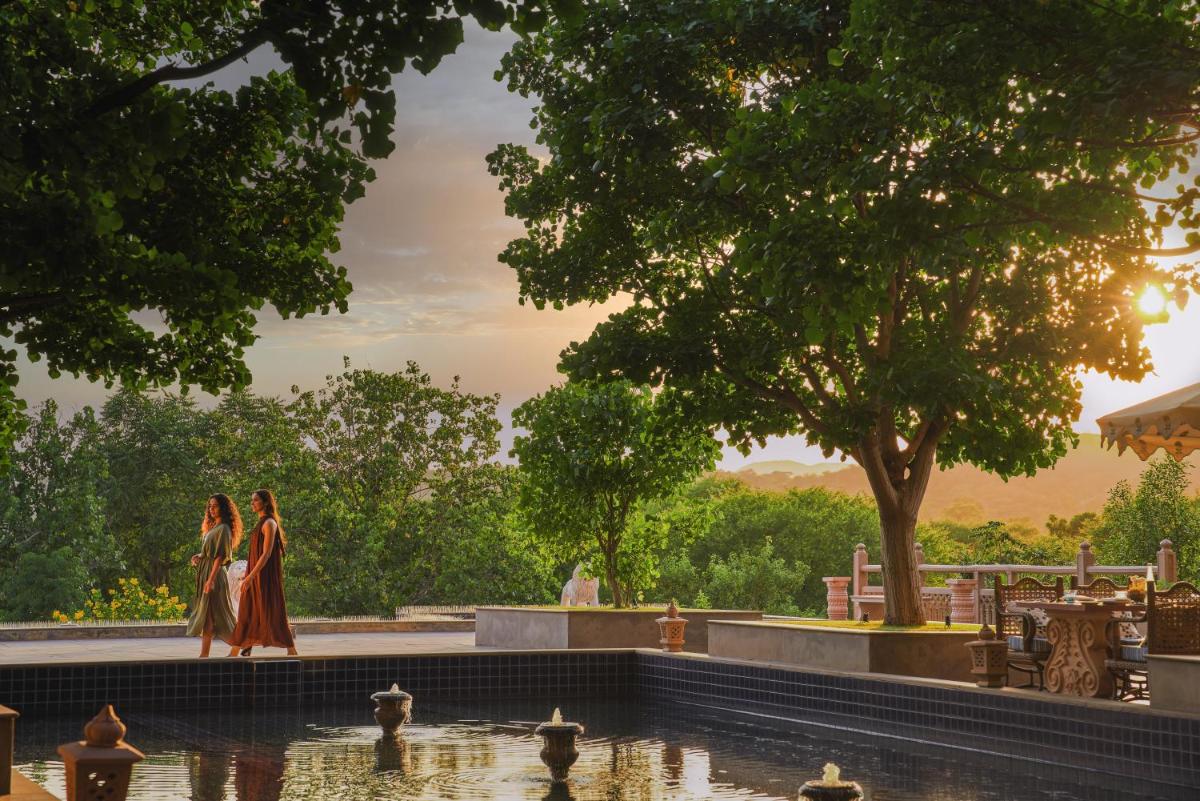 two women walking by a pond in a park at Fairmont Jaipur in Jaipur
