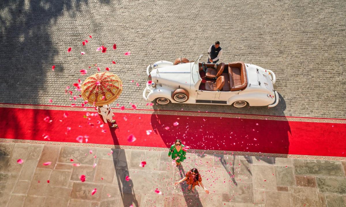 a man standing next to a white car on the street at Fairmont Jaipur in Jaipur