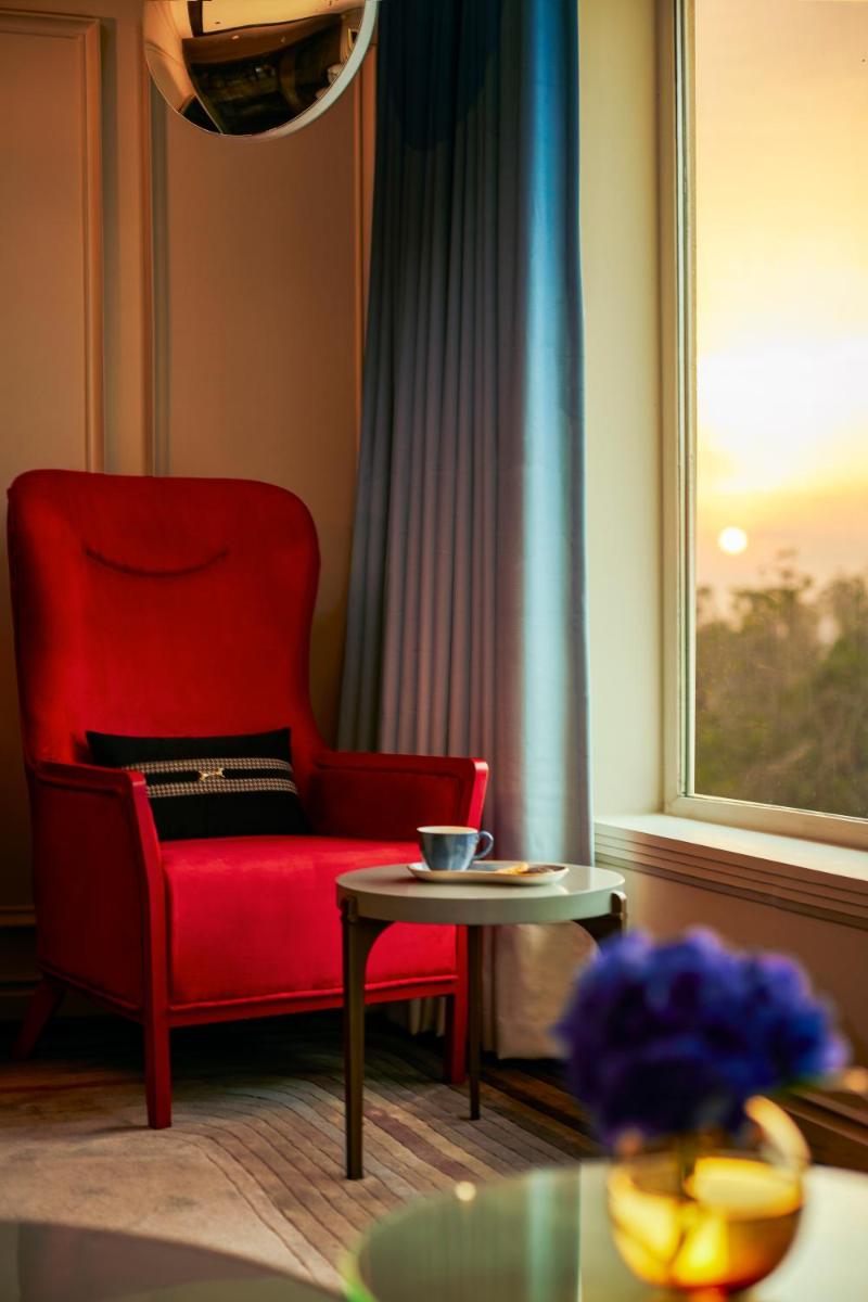 a red chair and a table in a room with a window at Hyatt Centric Sector17 Chandigarh in Chandīgarh