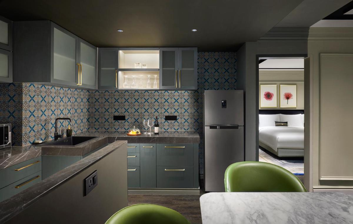 a kitchen with blue cabinets and green chairs at Hyatt Centric Sector17 Chandigarh in Chandīgarh