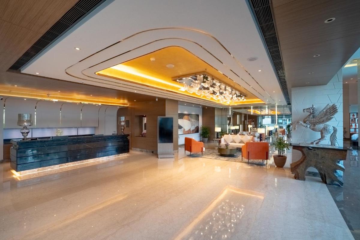 a lobby of a hotel with a waiting area at Radisson Blu Pune Hinjawadi in Pune a lobby of a hotel with a waiting area at Radisson Blu Pune Hinjawadi in Pune
