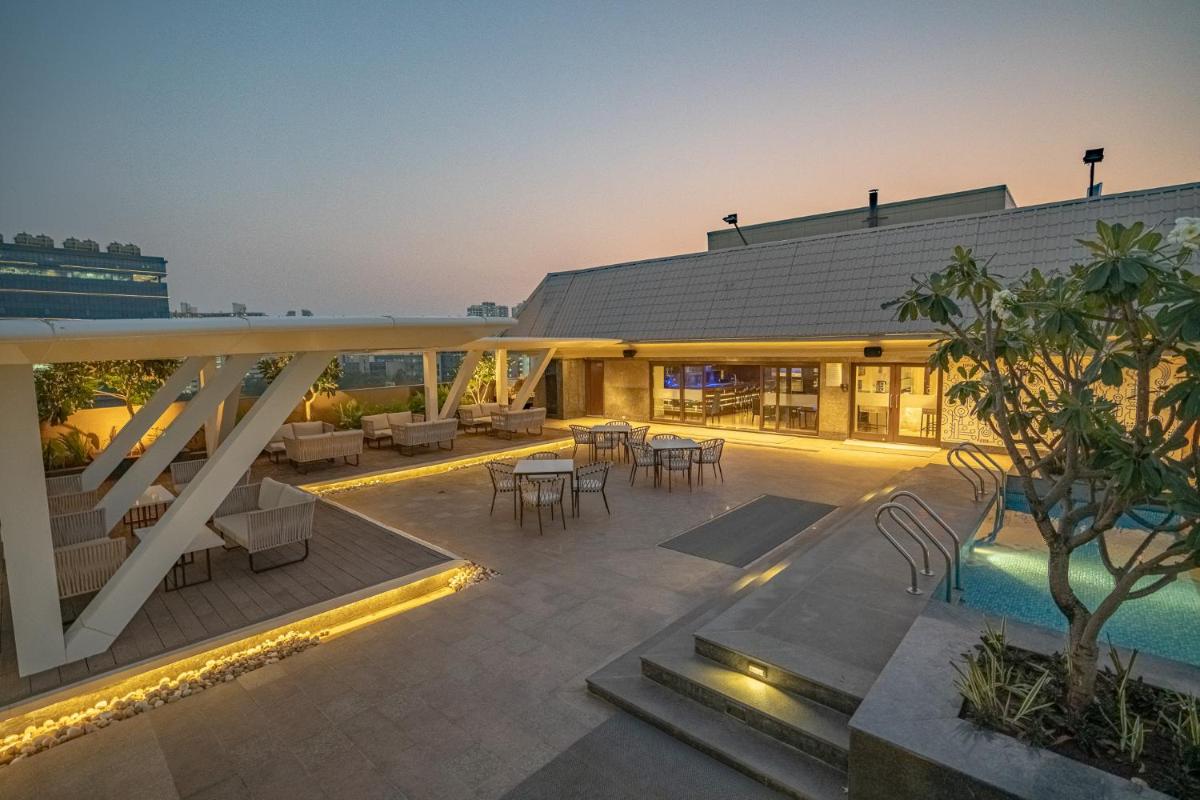 a building with a patio and a swimming pool at Radisson Blu Pune Hinjawadi in Pune a building with a patio and a swimming pool at Radisson Blu Pune Hinjawadi in Pune