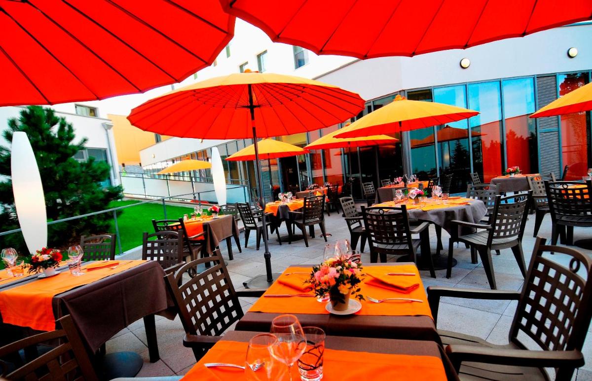 un restaurant avec des tables, des chaises et des parasols rouges dans l'établissement B&B HOME Lyon Centre Berthelot, à Lyon