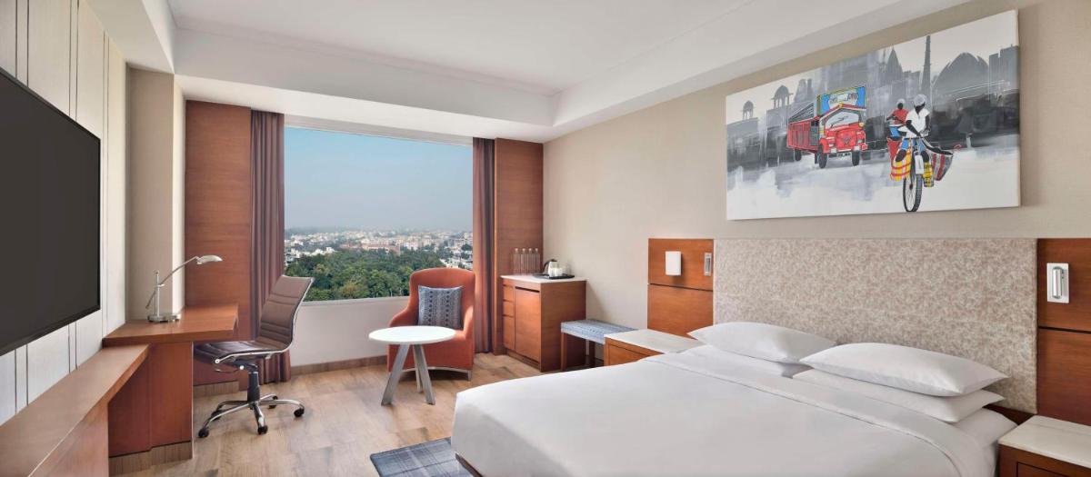 a bedroom with a bed and a desk and a window at Hyatt Centric Janakpuri New Delhi in New Delhi