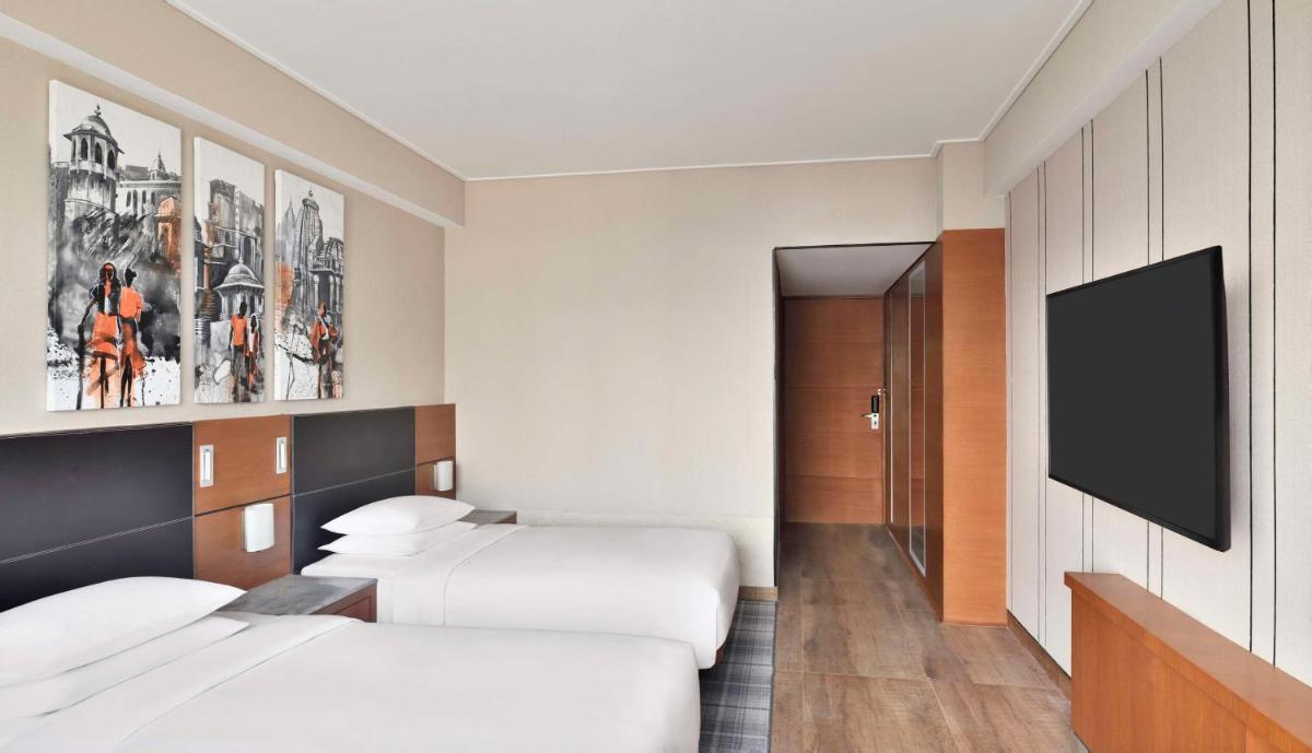 a hotel room with two beds and a flat screen tv at Hyatt Centric Janakpuri New Delhi in New Delhi