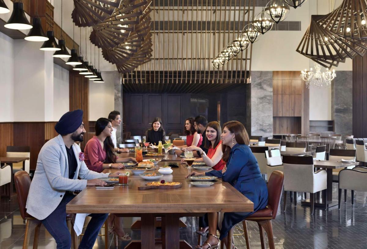 a group of people sitting at a table in a restaurant at Hyatt Centric Janakpuri New Delhi in New Delhi