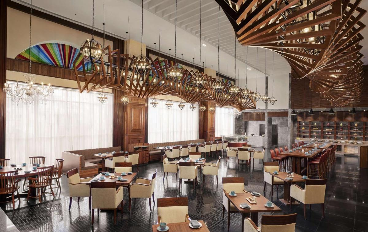 a restaurant with tables and chairs and chandeliers at Hyatt Centric Janakpuri New Delhi in New Delhi