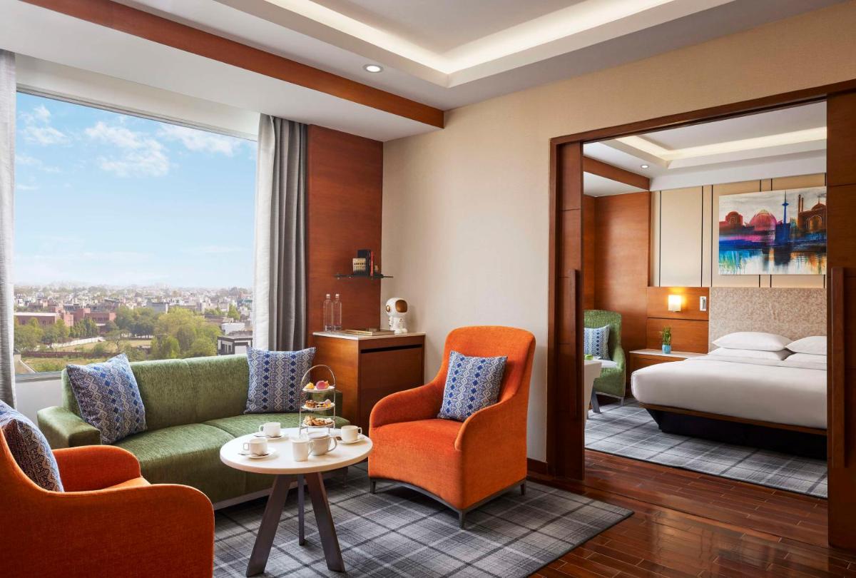 a hotel room with a bed and a couch and chairs at Hyatt Centric Janakpuri New Delhi in New Delhi +101 photos