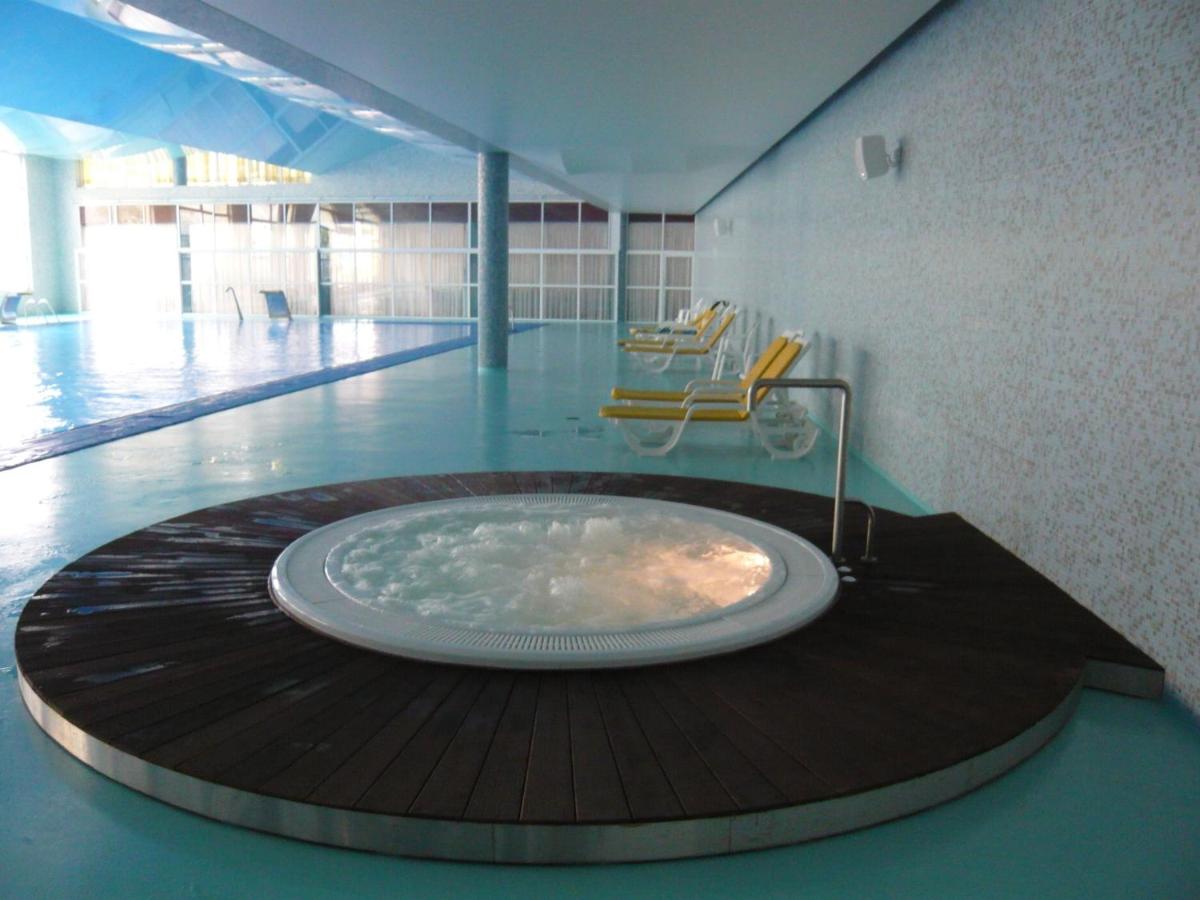 uma grande banheira num quarto com piscina em D. Afonso Hotel & SPA em Monte Real