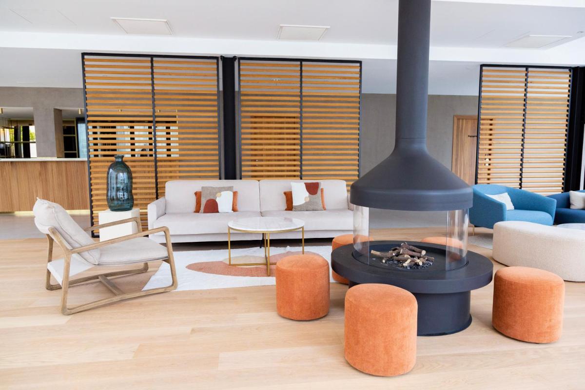 - un salon avec une cheminée, un canapé et des chaises dans l'établissement Paxton Paris MLV, à Ferrières-en-Brie