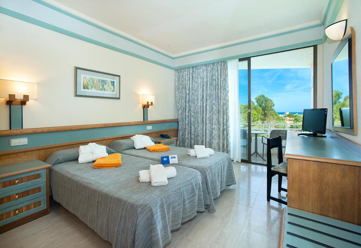 Una habitación de hotel con dos camas y un televisor. en Exagon Park, en Can Picafort