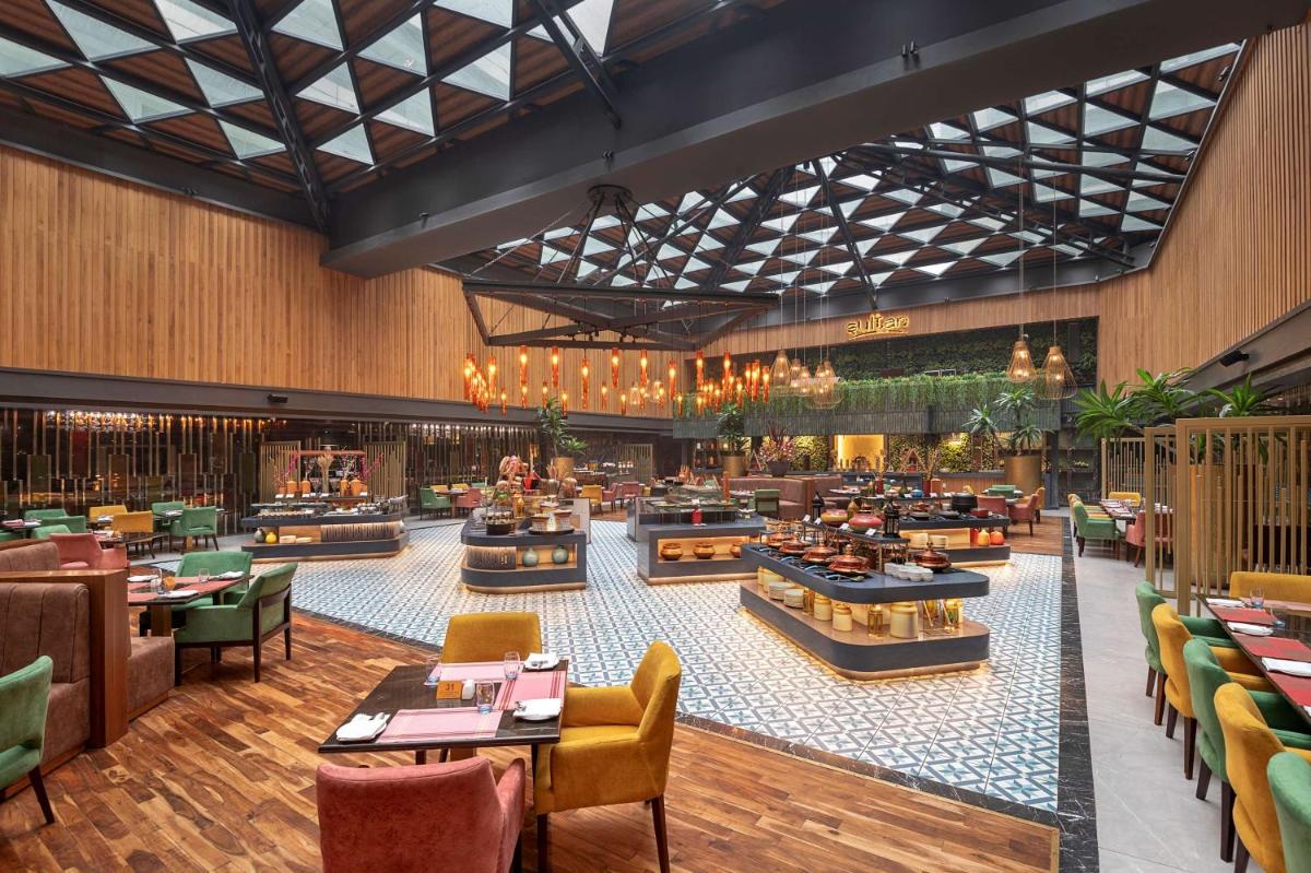 a restaurant with tables and chairs in a building at Radisson Blu Kaushambi Delhi NCR in Ghaziabad +66 photos