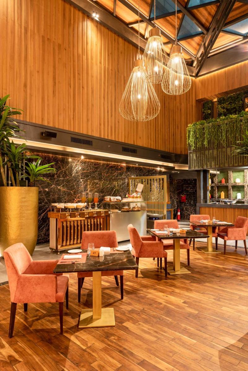 a restaurant with tables and chairs and chandeliers at Radisson Blu Kaushambi Delhi NCR in Ghaziabad