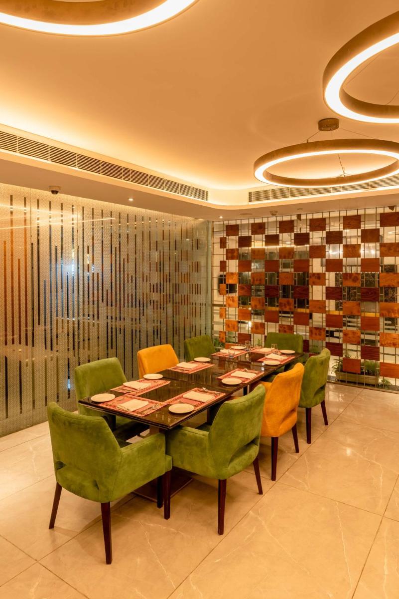 a dining room with a long table and green chairs at Radisson Blu Kaushambi Delhi NCR in Ghaziabad