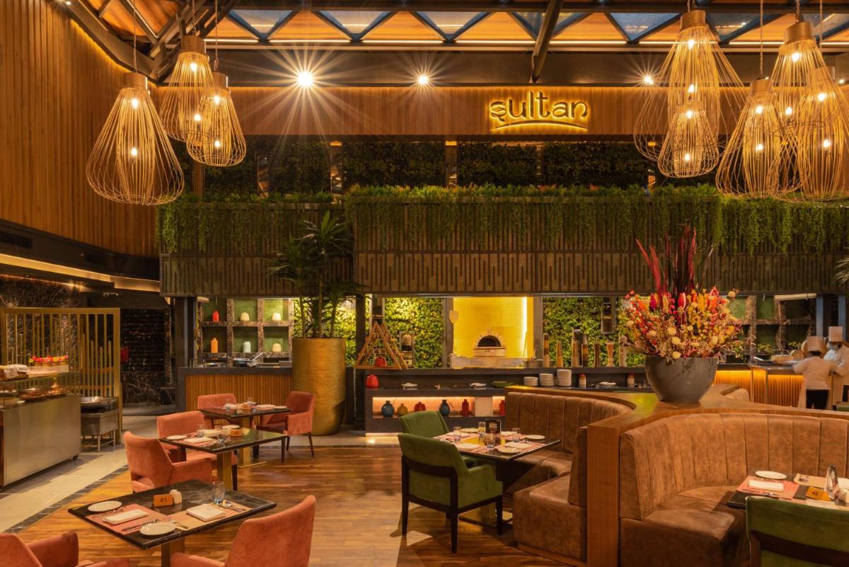 a restaurant with tables and chairs and lights at Radisson Blu Kaushambi Delhi NCR in Ghaziabad