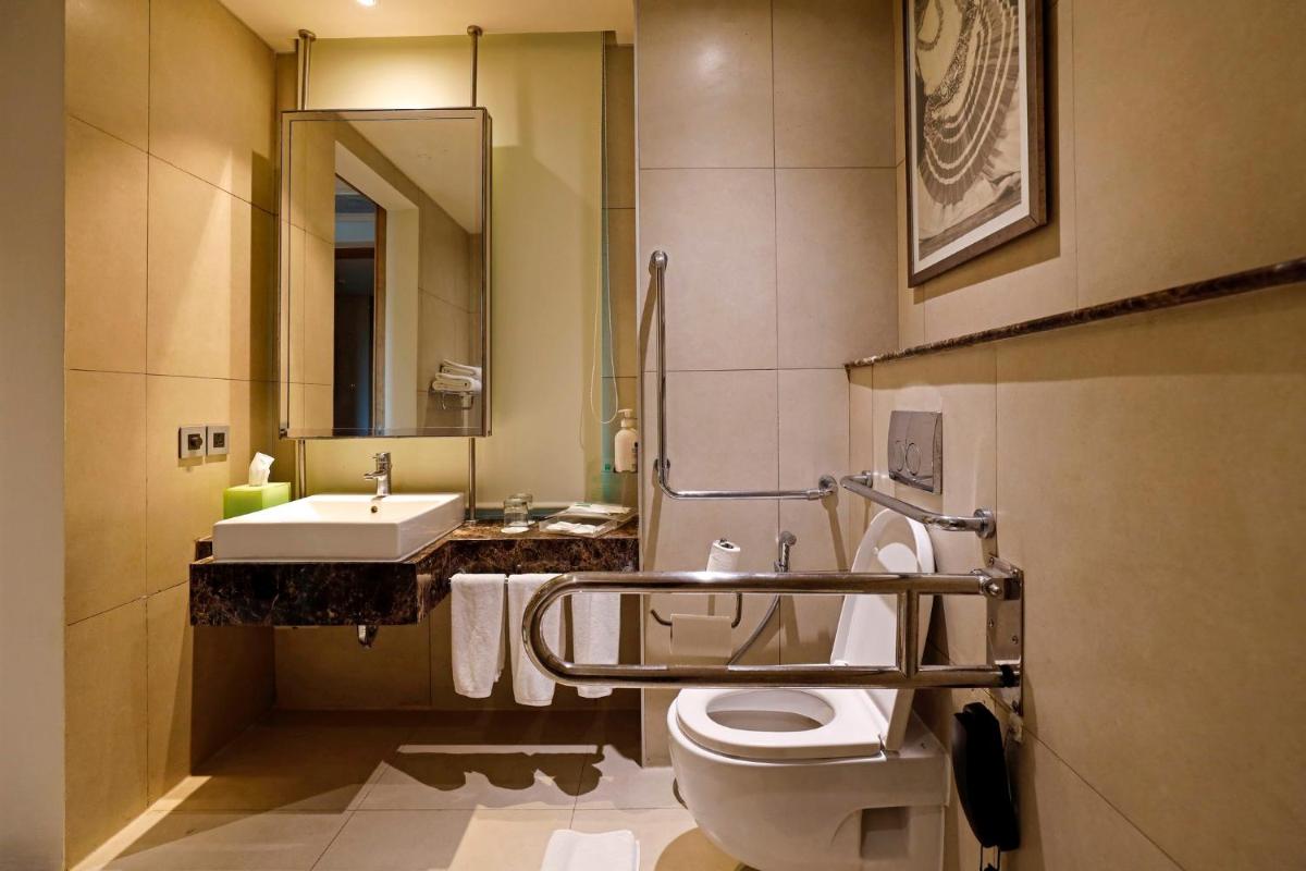 a bathroom with a toilet and a sink and a mirror at Holiday Inn Chennai OMR IT Expressway by IHG in Chennai