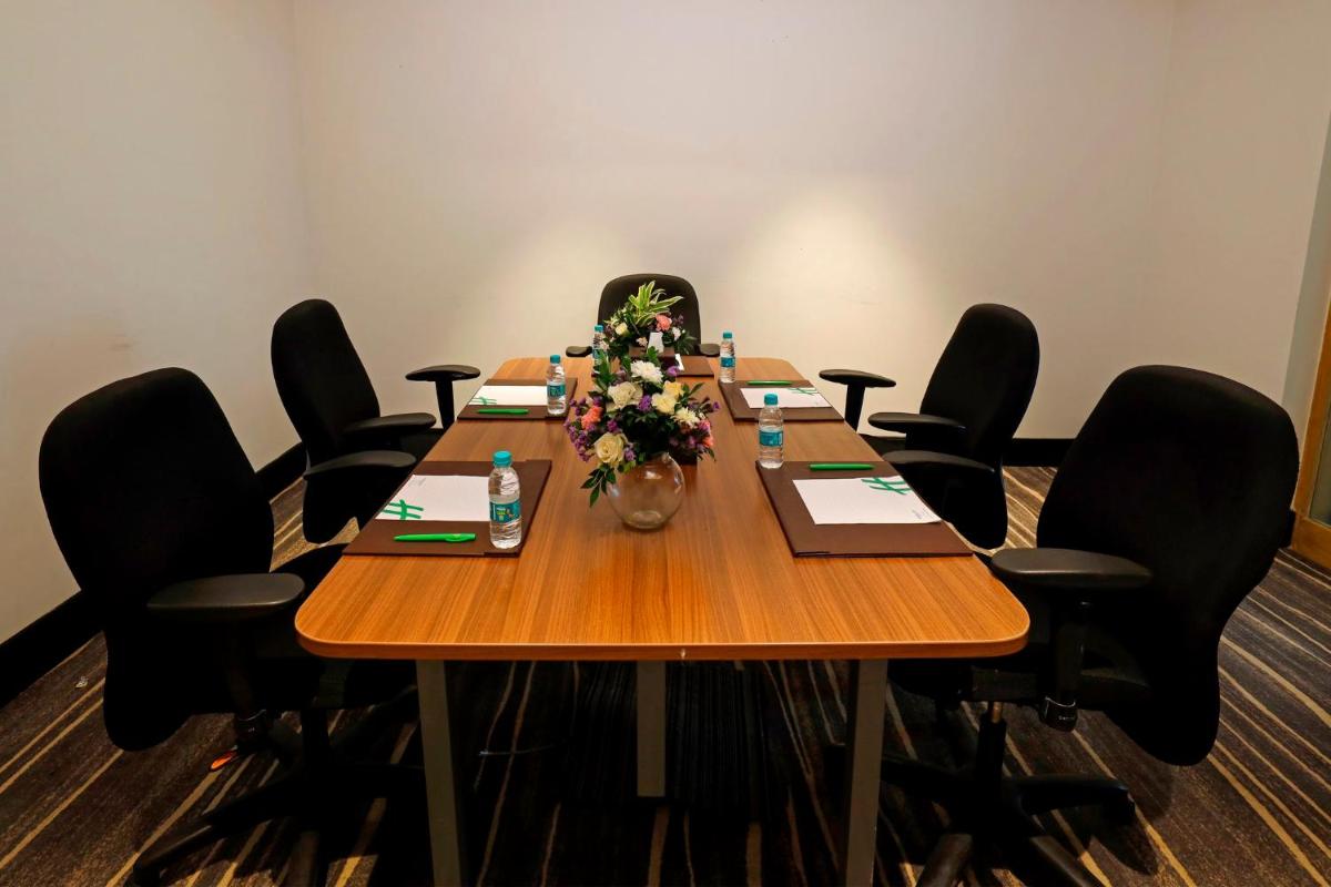 a conference room with a long wooden table with black chairs at Holiday Inn Chennai OMR IT Expressway by IHG in Chennai